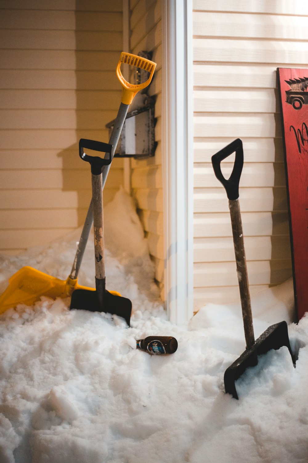 red and black shovel on snow covered ground