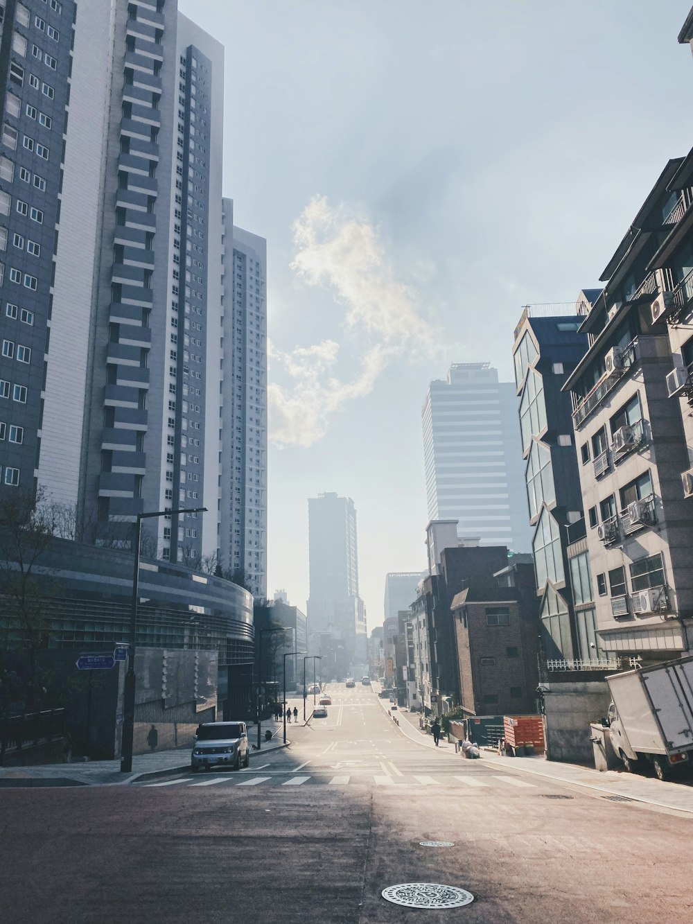 cars on road between high rise buildings during daytime