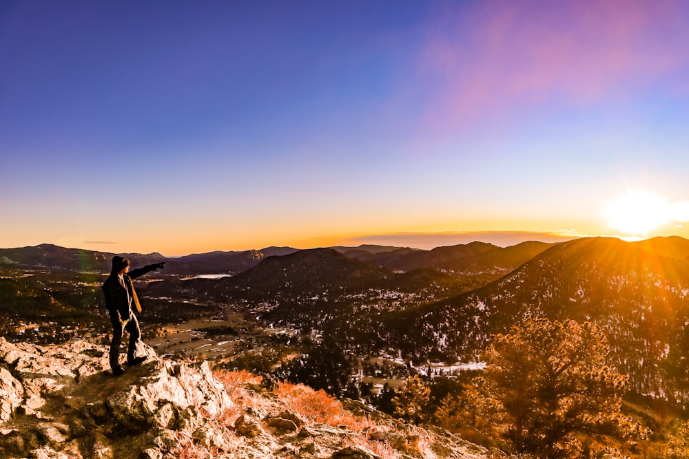 man in black jacket standing on brown rock formation during daytime