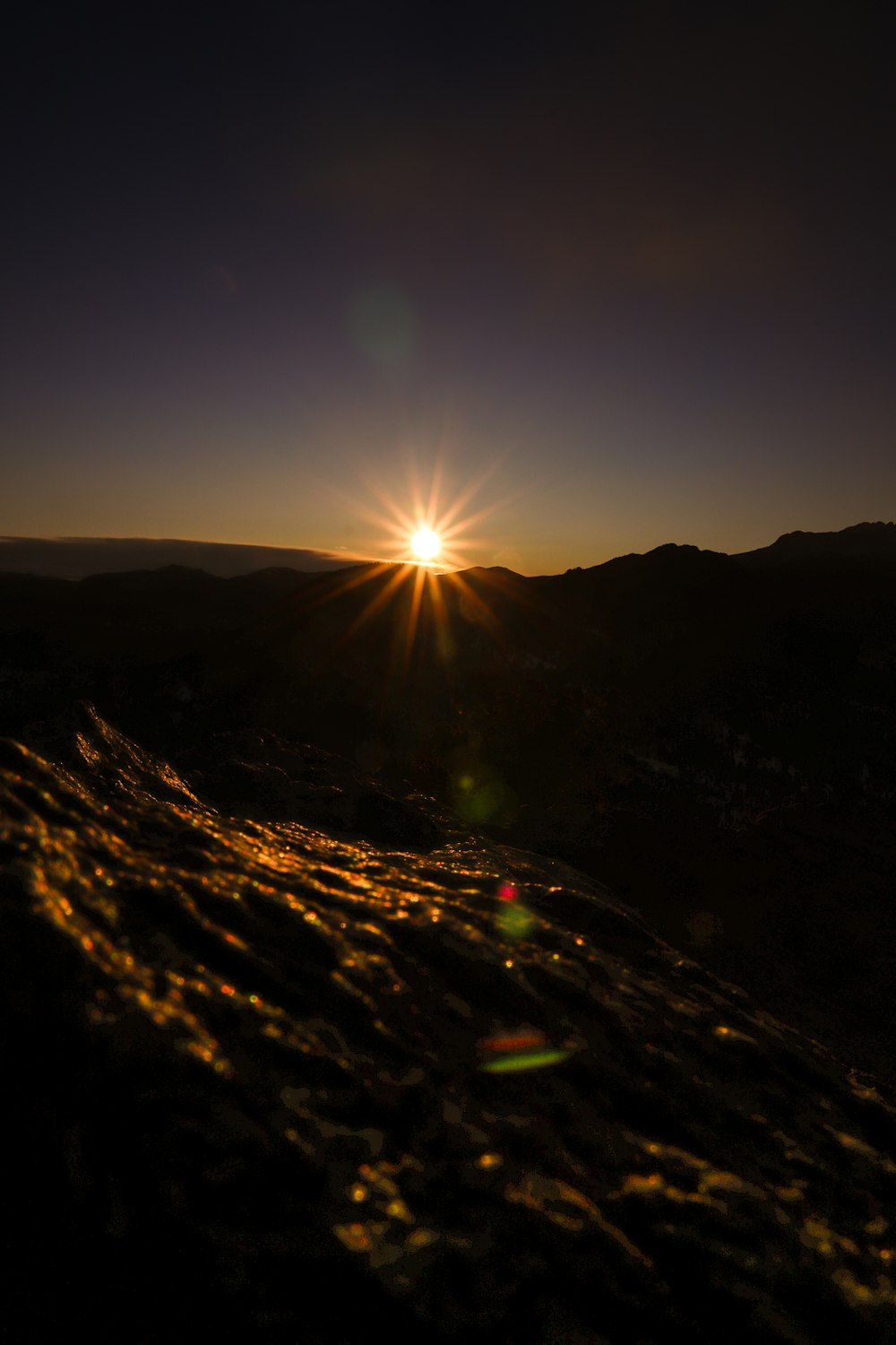 the sun is setting over a mountain range