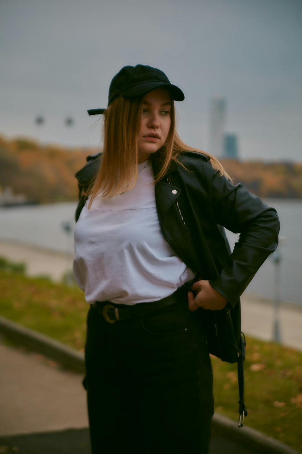 woman in black leather jacket and black pants standing on road during daytime