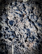 Rough, intricate textures of dark volcanic rock, appearing porous and rugged, with variations in shadow creating depth.