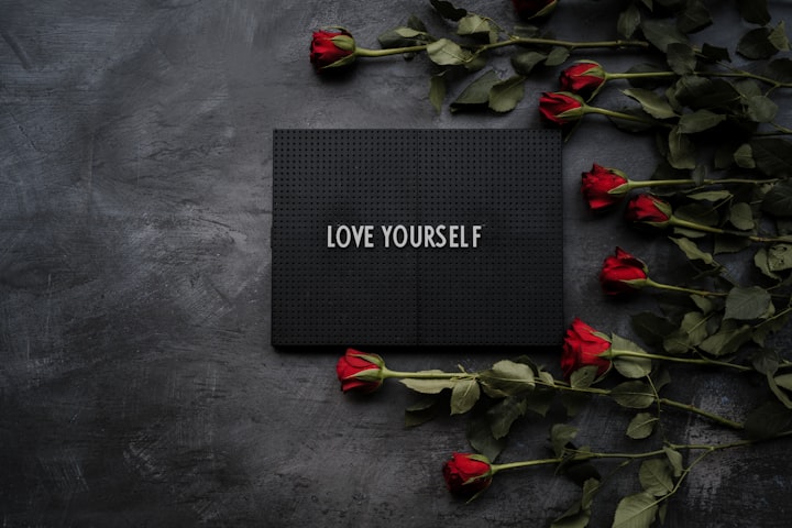 A tablet written love yourself with roses on the side