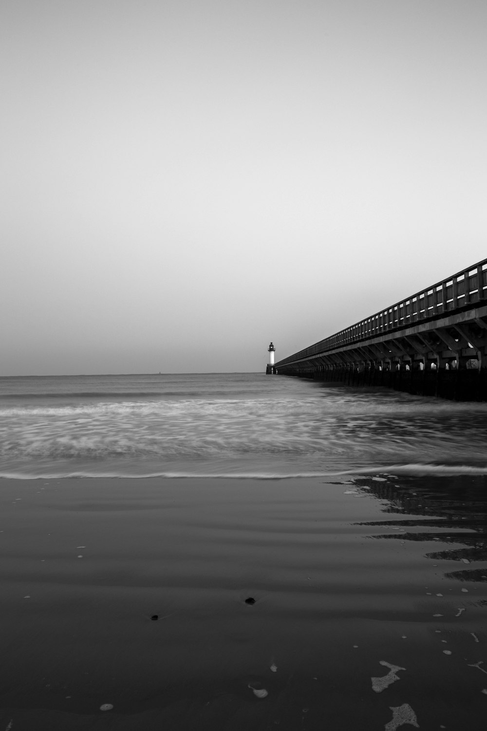 Foto en escala de grises de un muelle de madera en el mar
