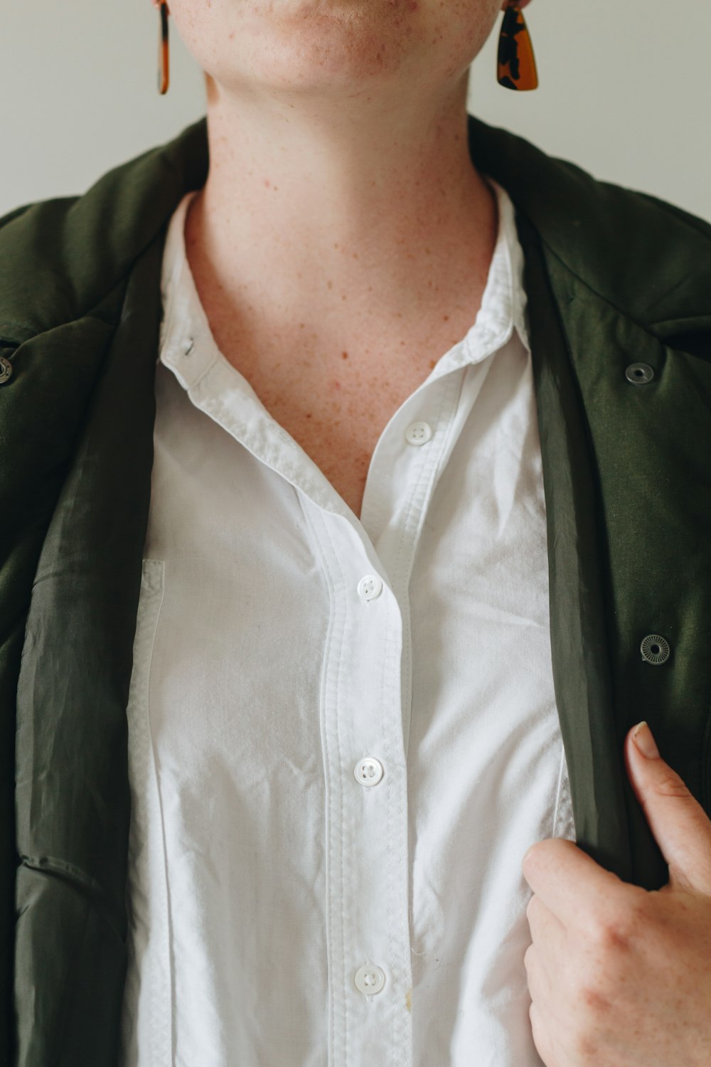 person in white button up shirt and green coat