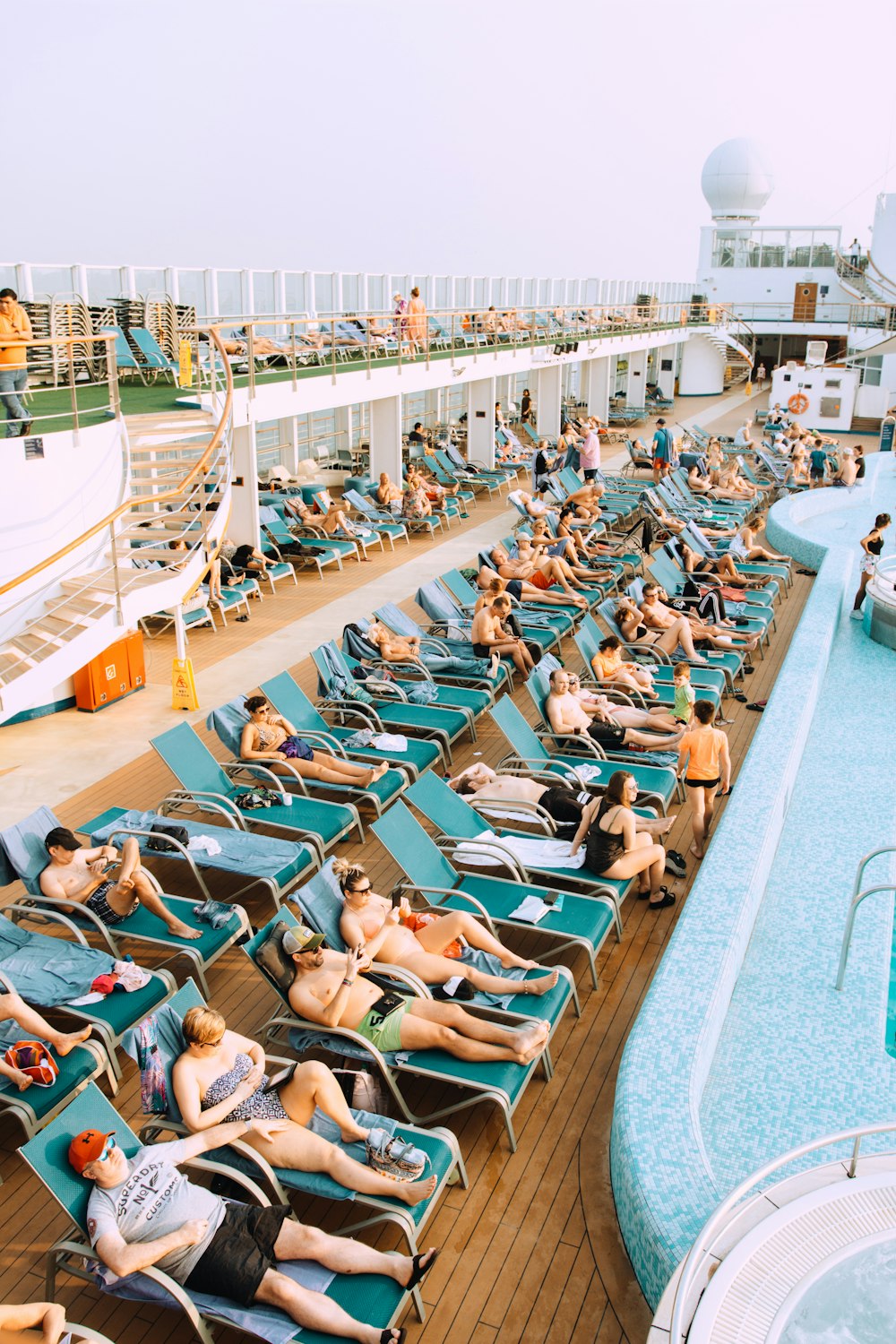 people lying on blue and white lounge chairs