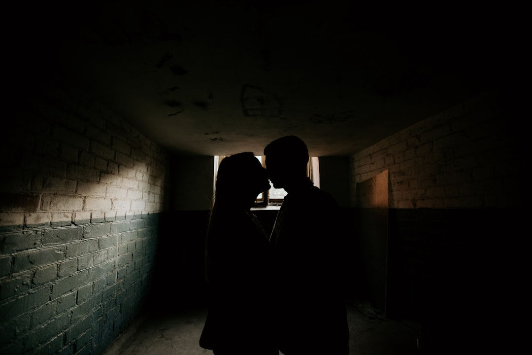 silhouette of man in black suit standing in front of white brick wall