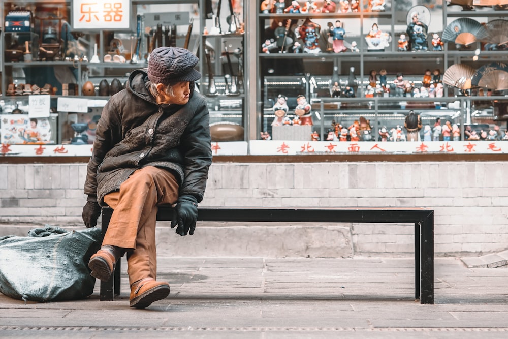 man in brown coat sitting on concrete bench