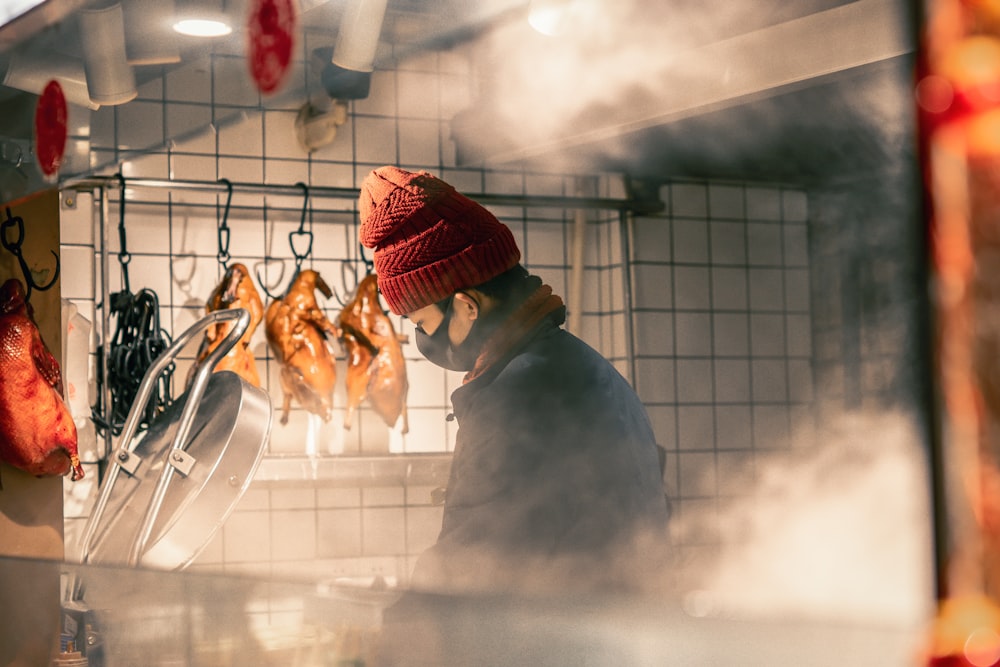 man in red knit cap and white long sleeve shirt holding brown bread