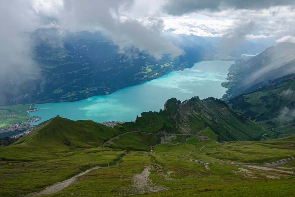 green and brown mountains near blue lake under white clouds during daytime