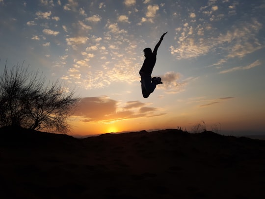 silhouette of person jumping during sunset in Maranjab Desert Iran