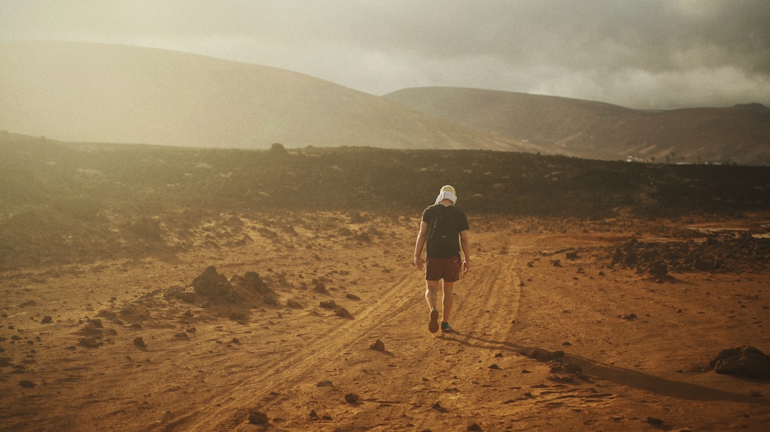 man in brown jacket walking on brown sand during daytime