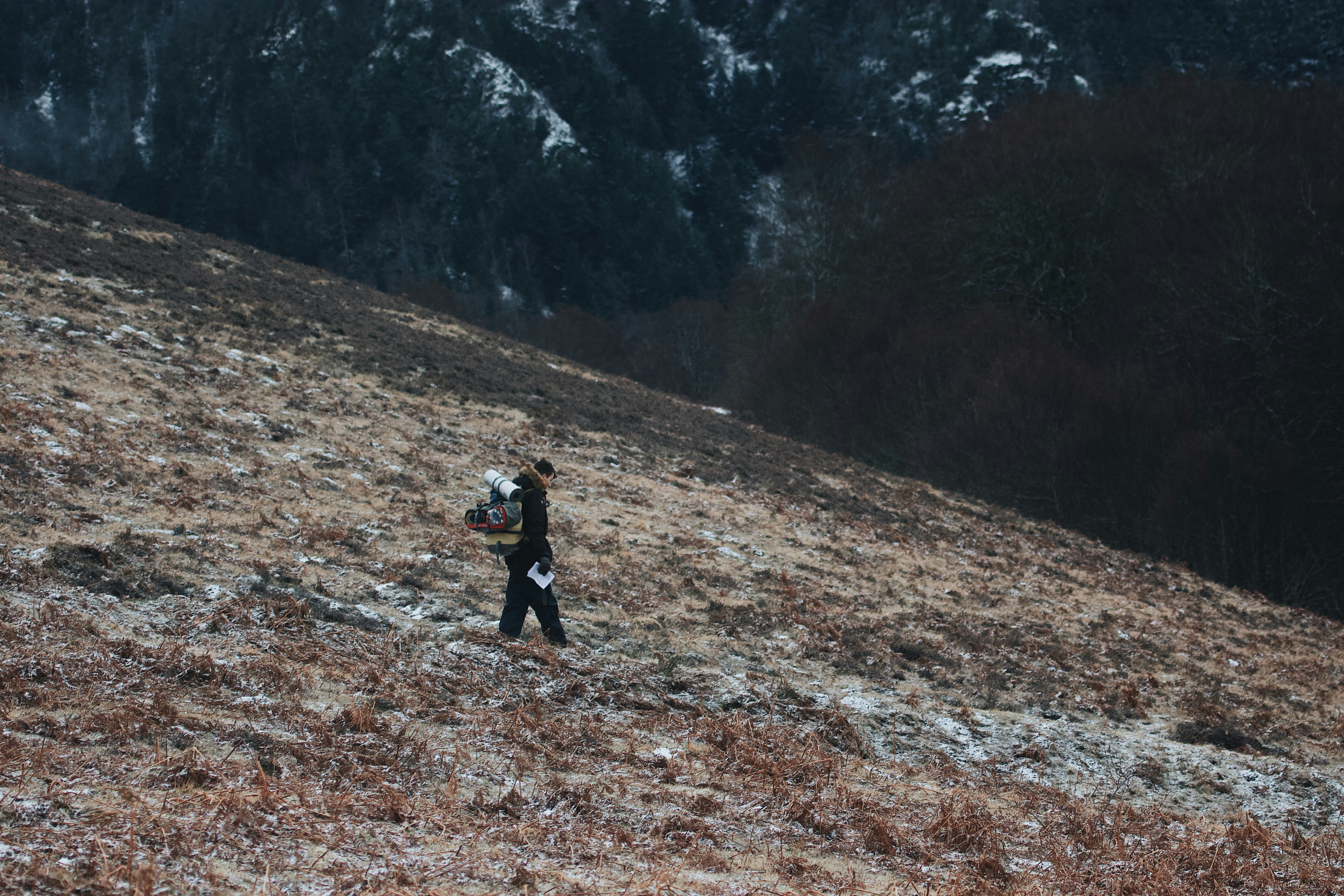 person in black jacket walking on brown dirt road during daytime