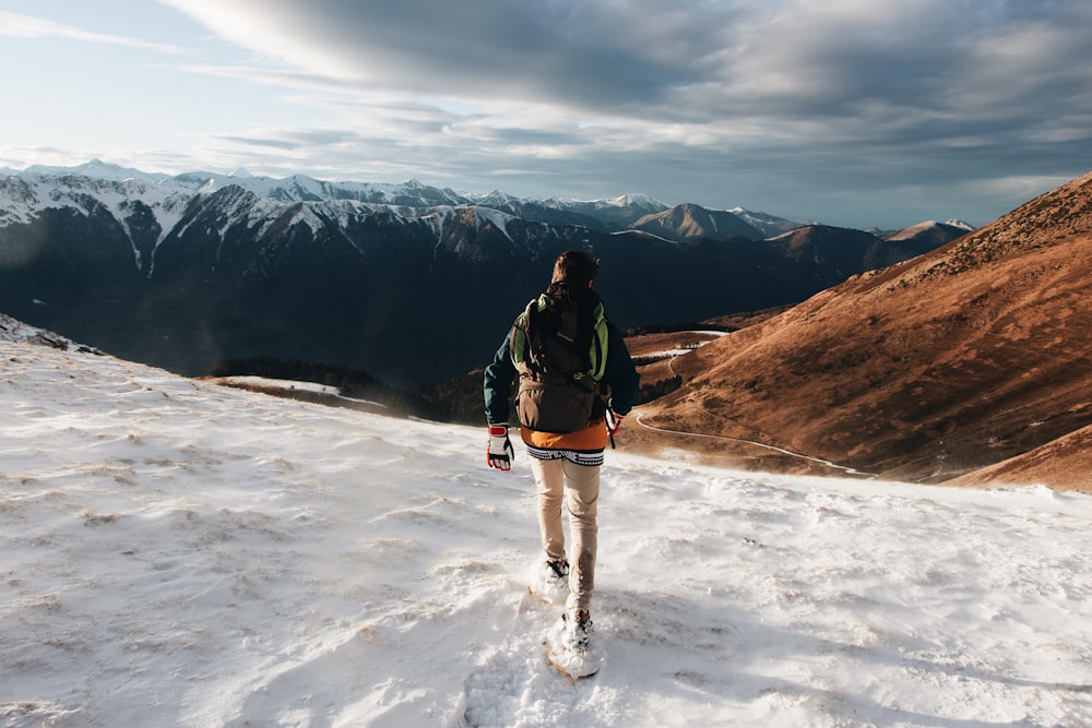 man in black jacket and blue denim jeans standing on snow covered ground