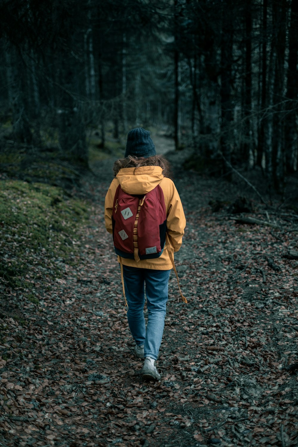 person in brown jacket and blue denim jeans walking on dirt road during daytime