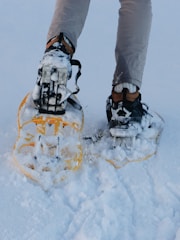 person in gray pants and black and orange hiking shoes standing on snow covered ground during