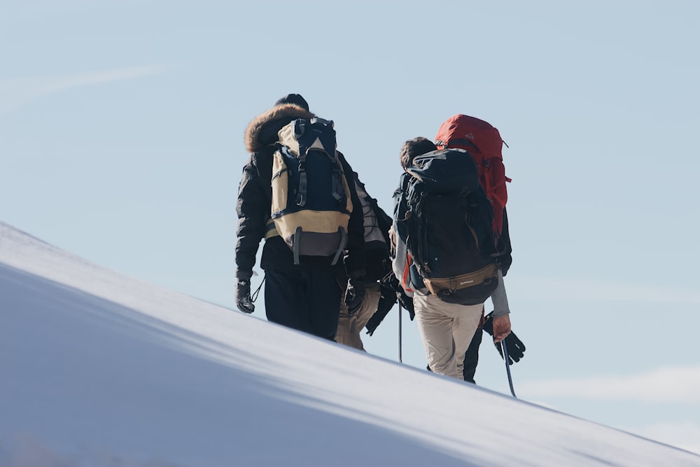 3 person in black jacket and red knit cap standing on snow covered ground during daytime