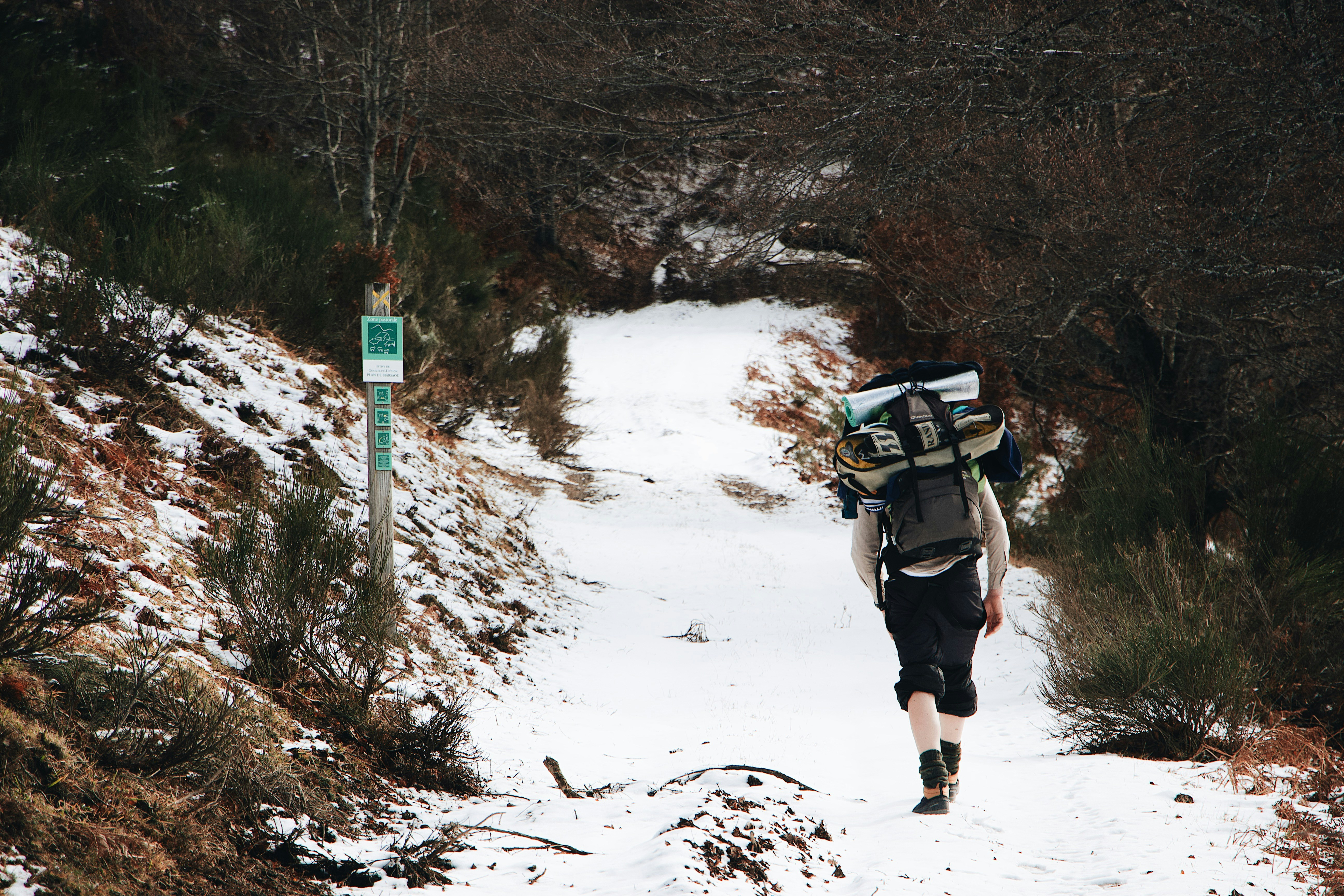 person in black jacket and black pants walking on snow covered ground during daytime