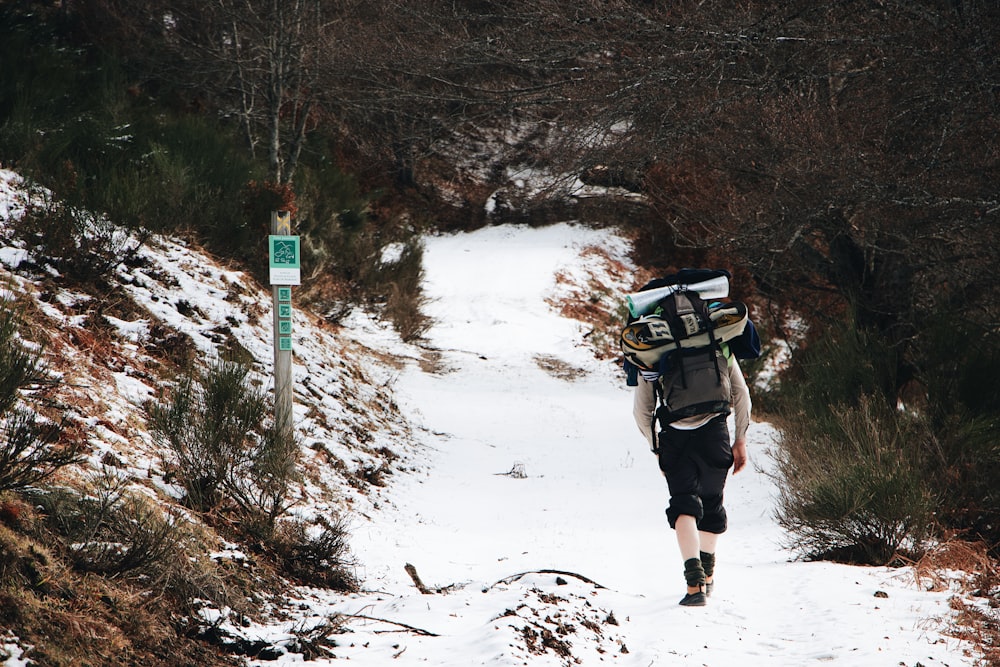 person in black jacket and black pants walking on snow covered ground during daytime