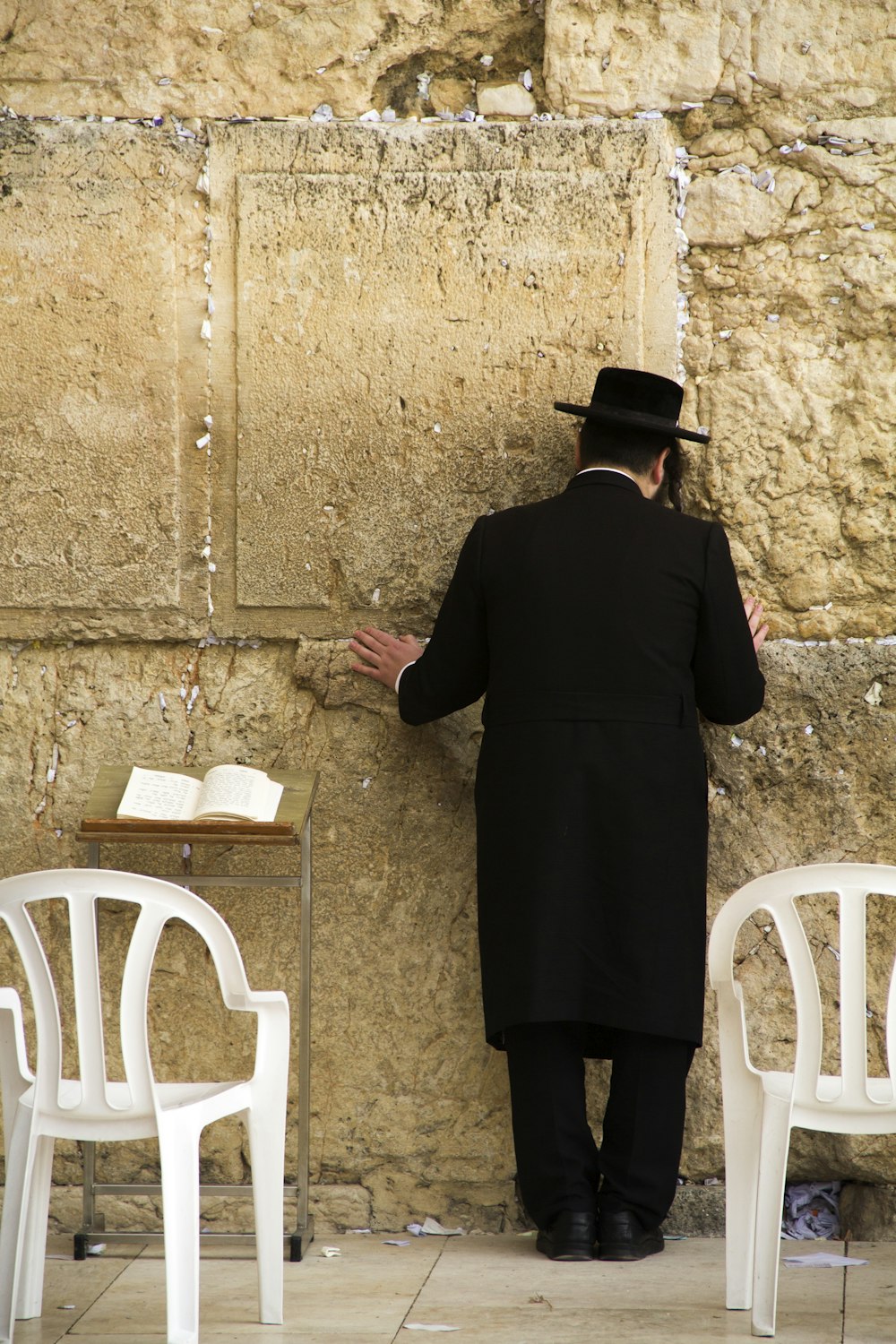 donna in abito nero a maniche lunghe in piedi vicino alla sedia di plastica bianca
