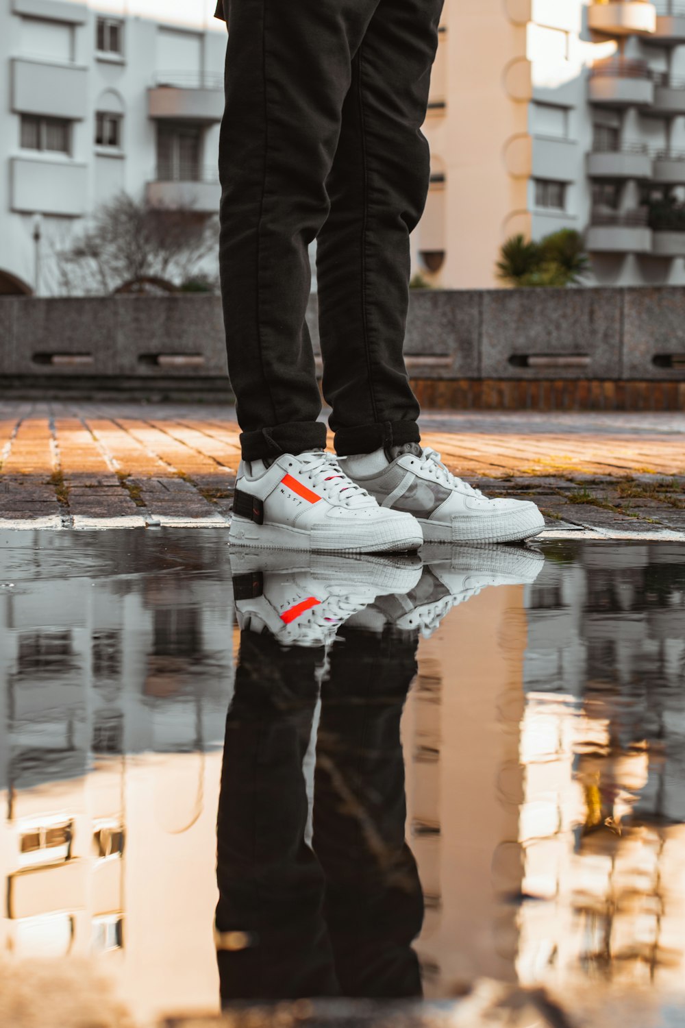 person in black pants and white nike sneakers standing on water