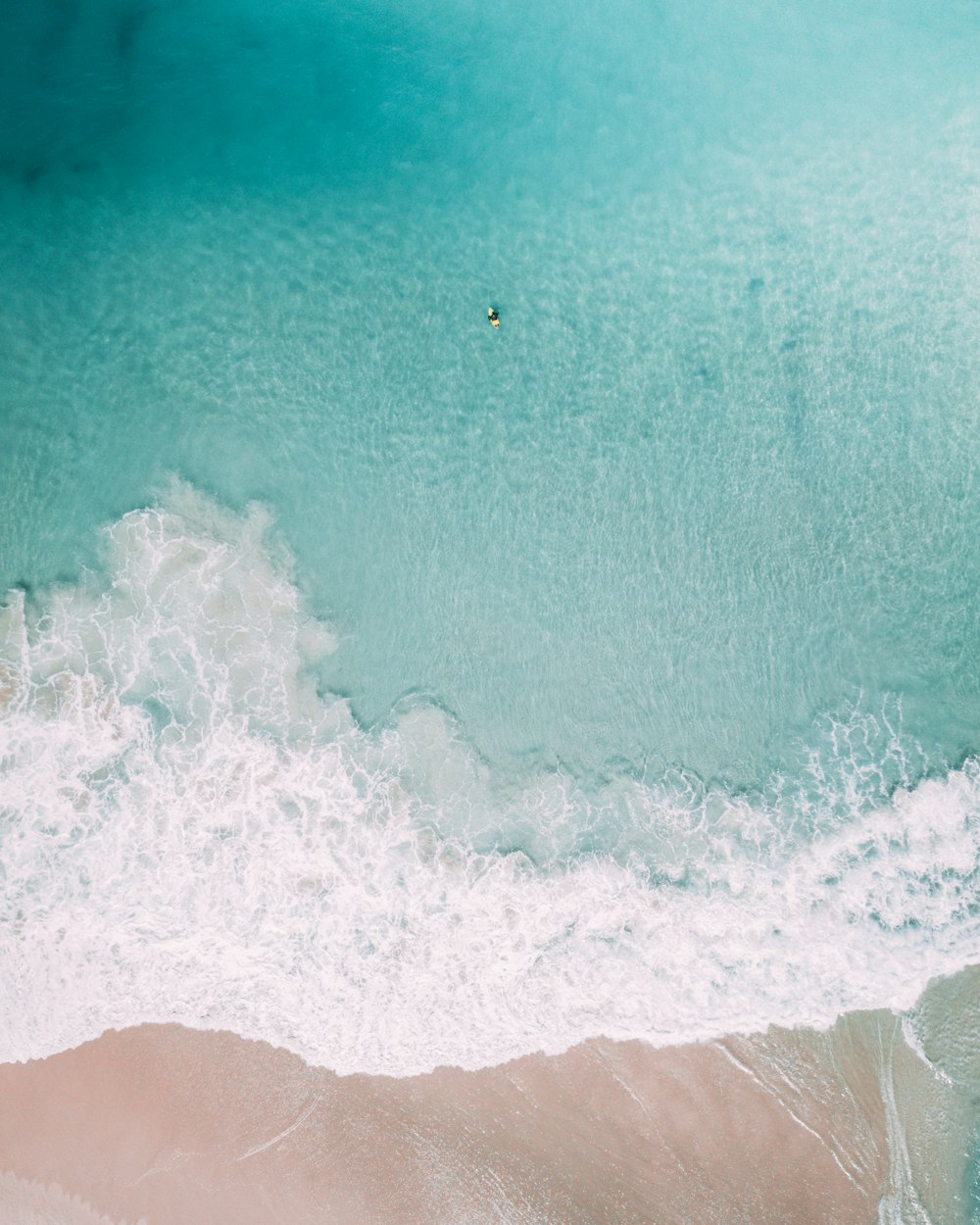 aerial view of ocean waves crashing on shore during daytime