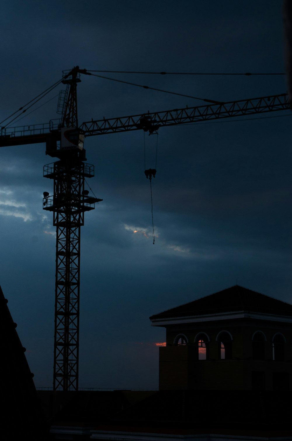 silhouette of crane under cloudy sky during sunset