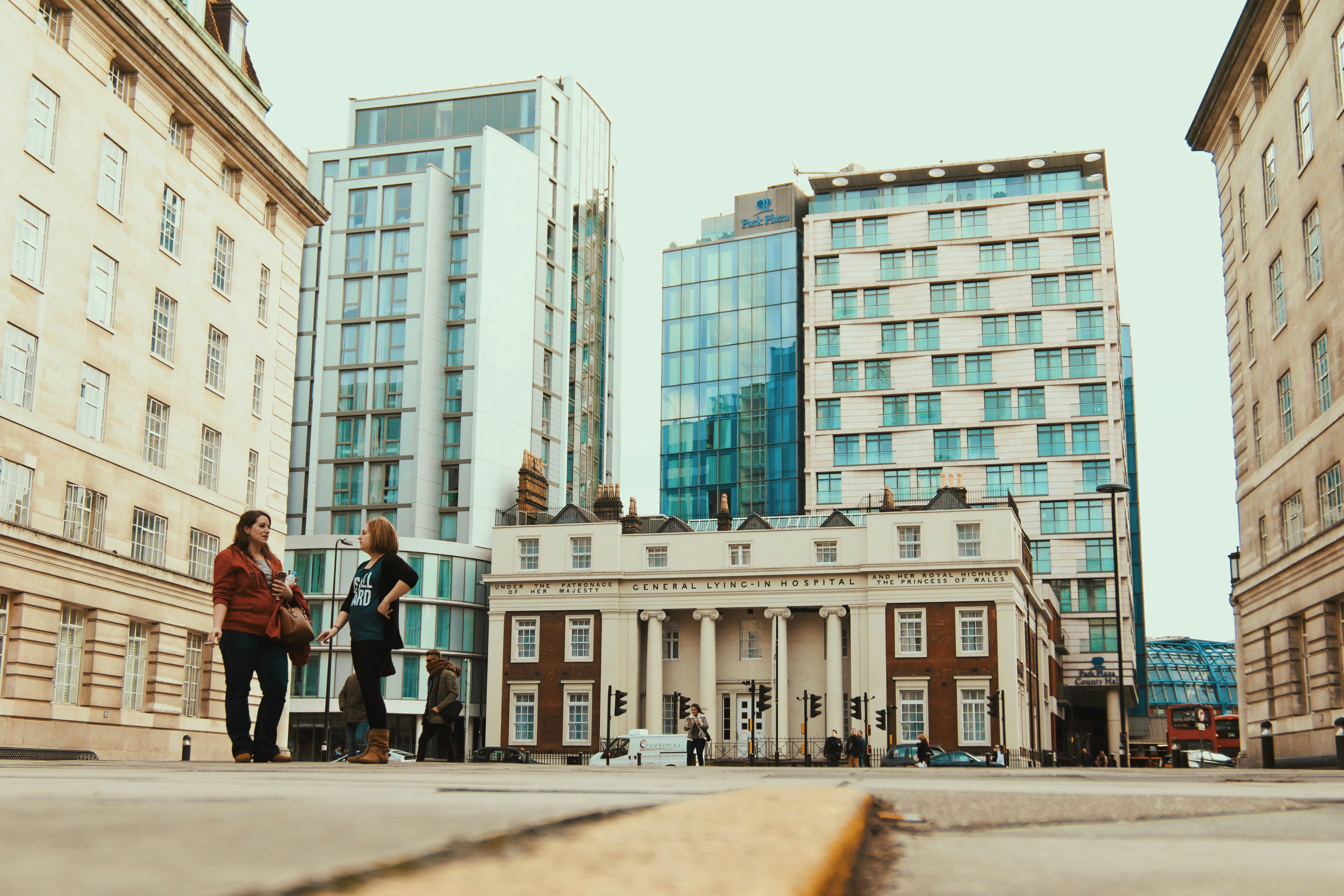 pessoas andando na calçada perto de um prédio de concreto branco durante o dia