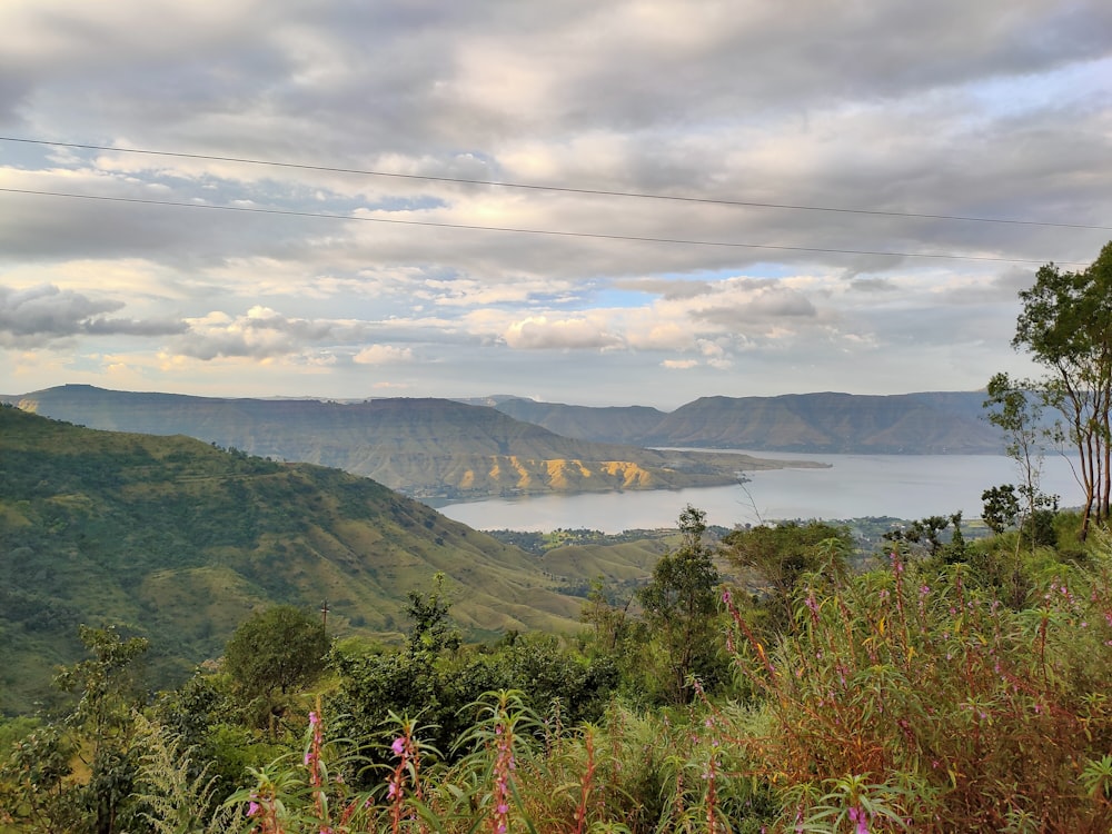 green mountain near body of water under cloudy sky during daytime