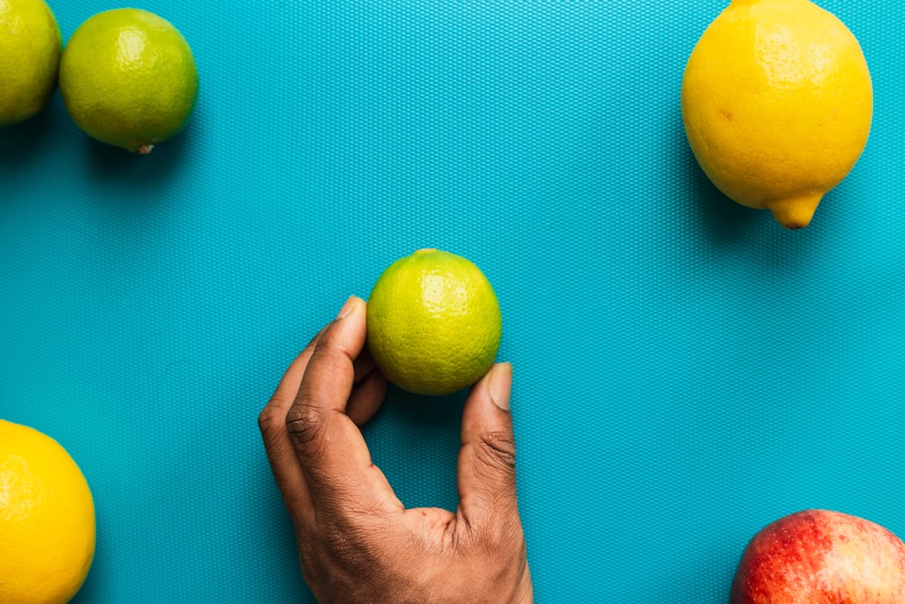 personne tenant un fruit de citron jaune