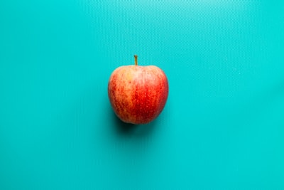 red apple fruit on blue surface