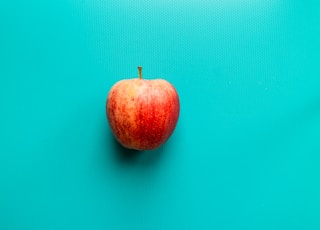 red apple fruit on blue surface