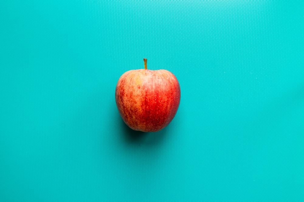 frutto di mela rossa su superficie blu