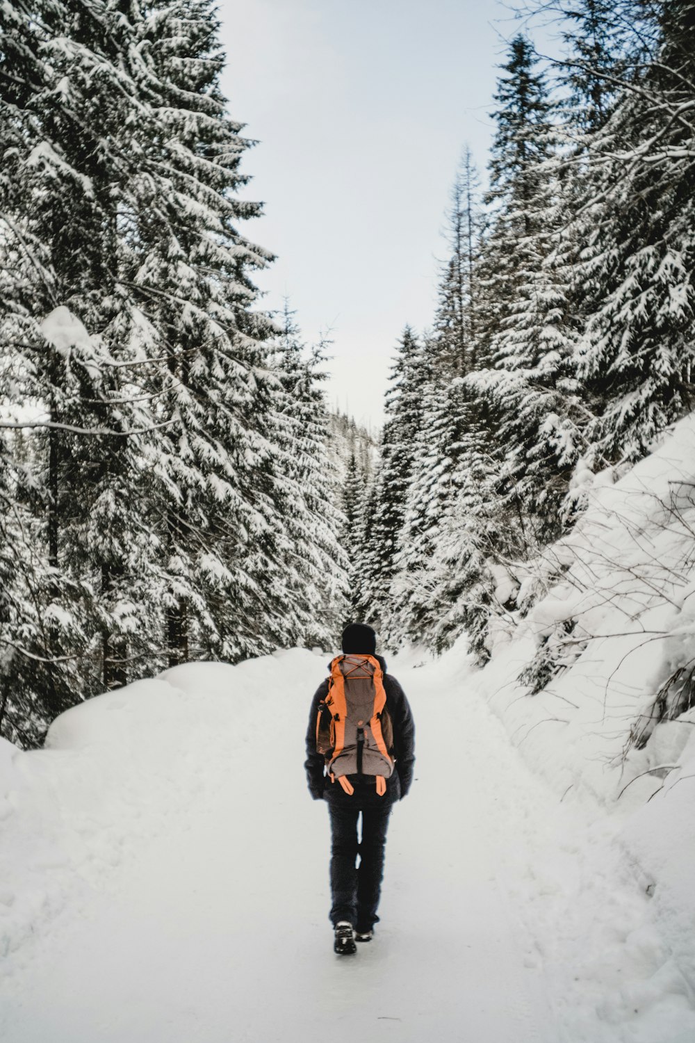 person in red jacket and black pants standing on snow covered ground