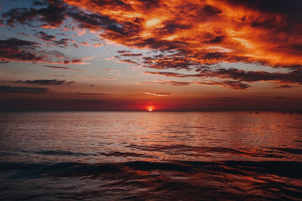 body of water under cloudy sky during sunset