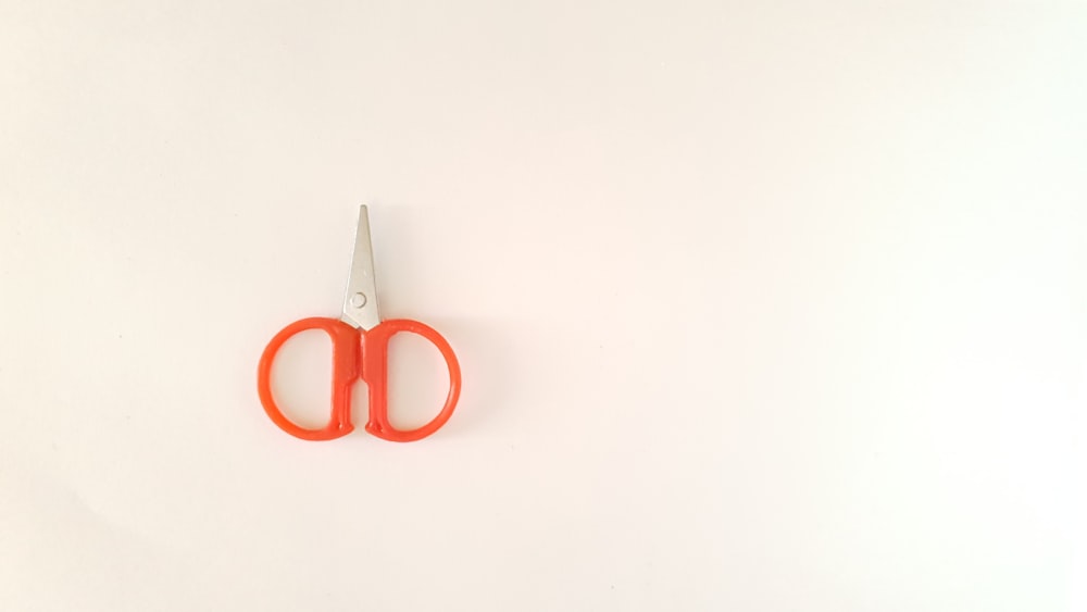 orange and silver scissors on white table