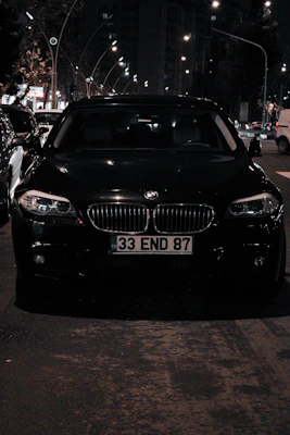 A sleek black BMW parked on a city street under soft evening light.