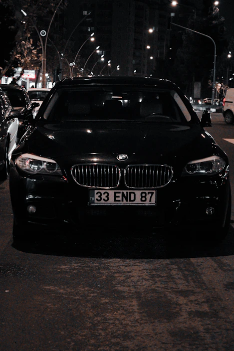 A sleek black BMW parked on a city street under soft evening light.
