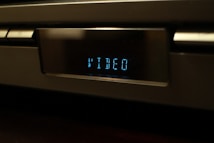 A close-up of a digital display on an electronic device showing the word 'VIDEO' in blue LED light. The device appears to be metallic and has a modern design.