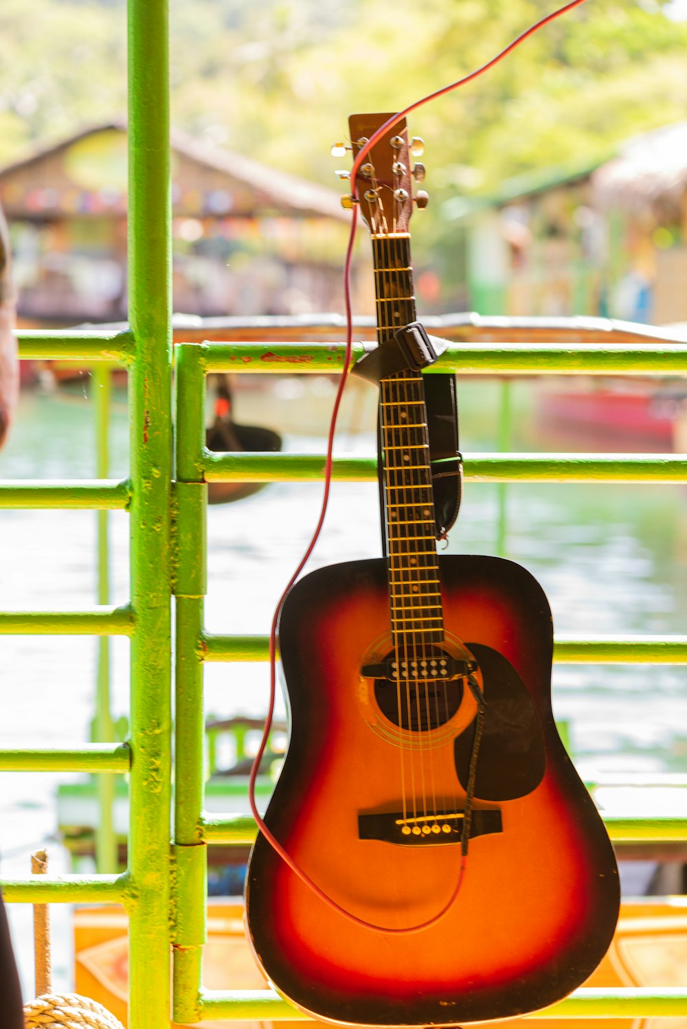 brown acoustic guitar on green metal fence