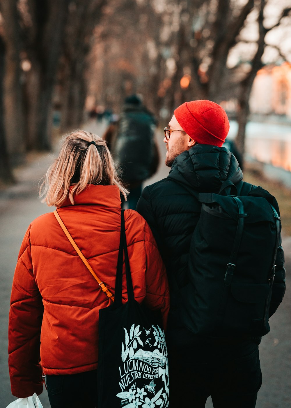 woman in red knit cap and red jacket standing in front of man in black jacket