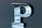 A metallic 3D letter 'P' with a smooth, reflective surface catching light and shadow. It stands out against a soft blue-gray background, presenting a modern, sleek appearance.
