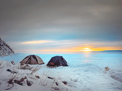 black tent on snow covered ground during sunset