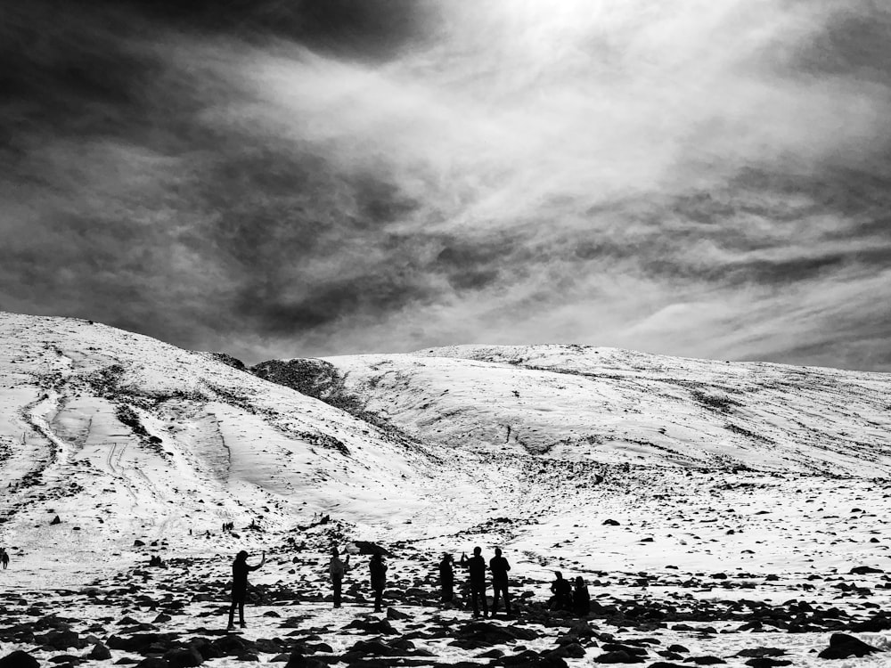 grayscale photo of people walking on snow covered ground