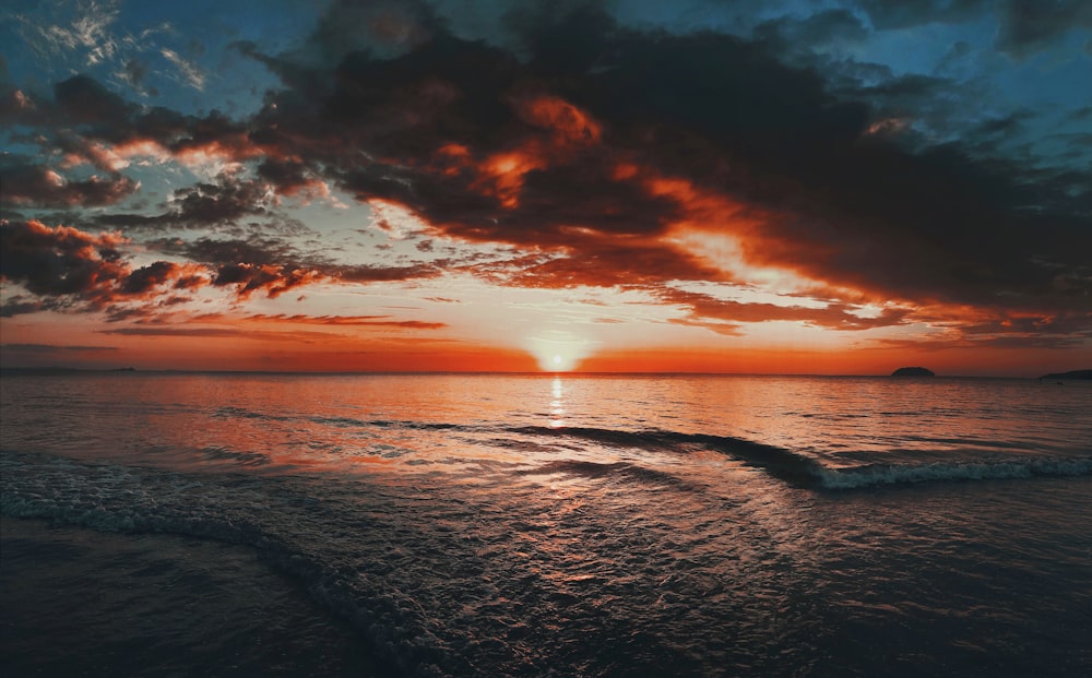 body of water under cloudy sky during sunset