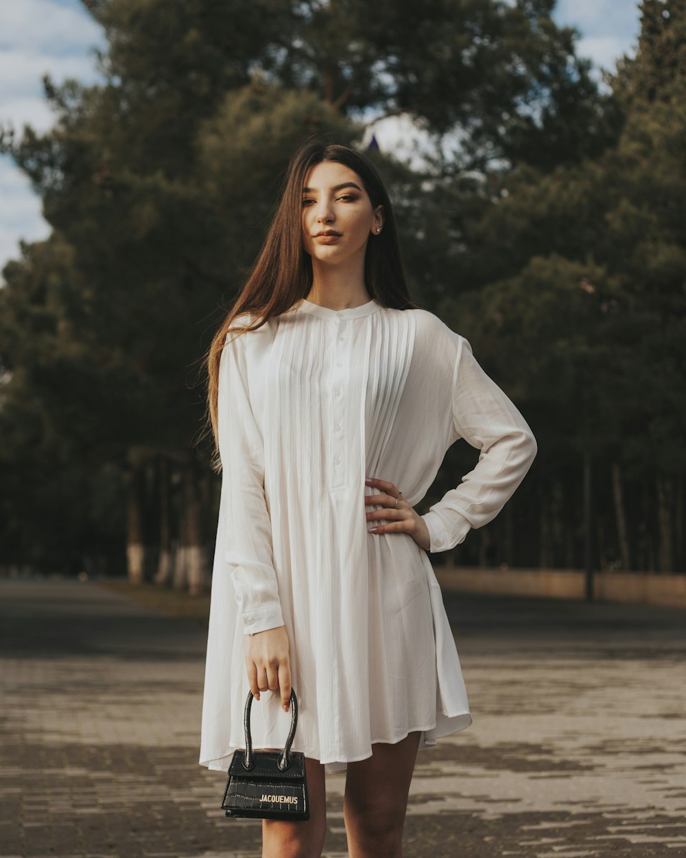 woman in white long sleeve dress standing on brown sand during daytime