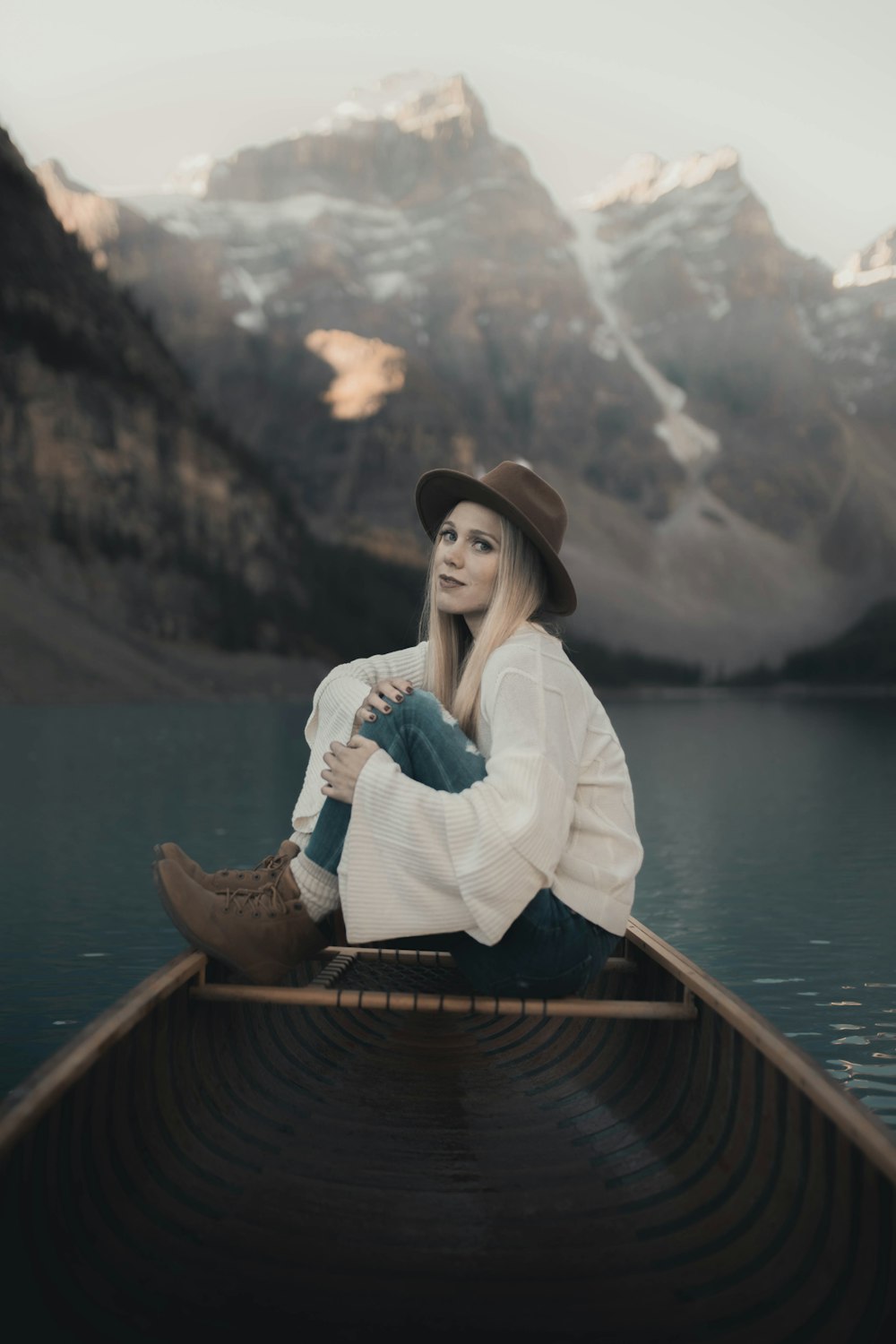 woman in white long sleeve shirt and brown hat sitting on brown wooden boat during daytime