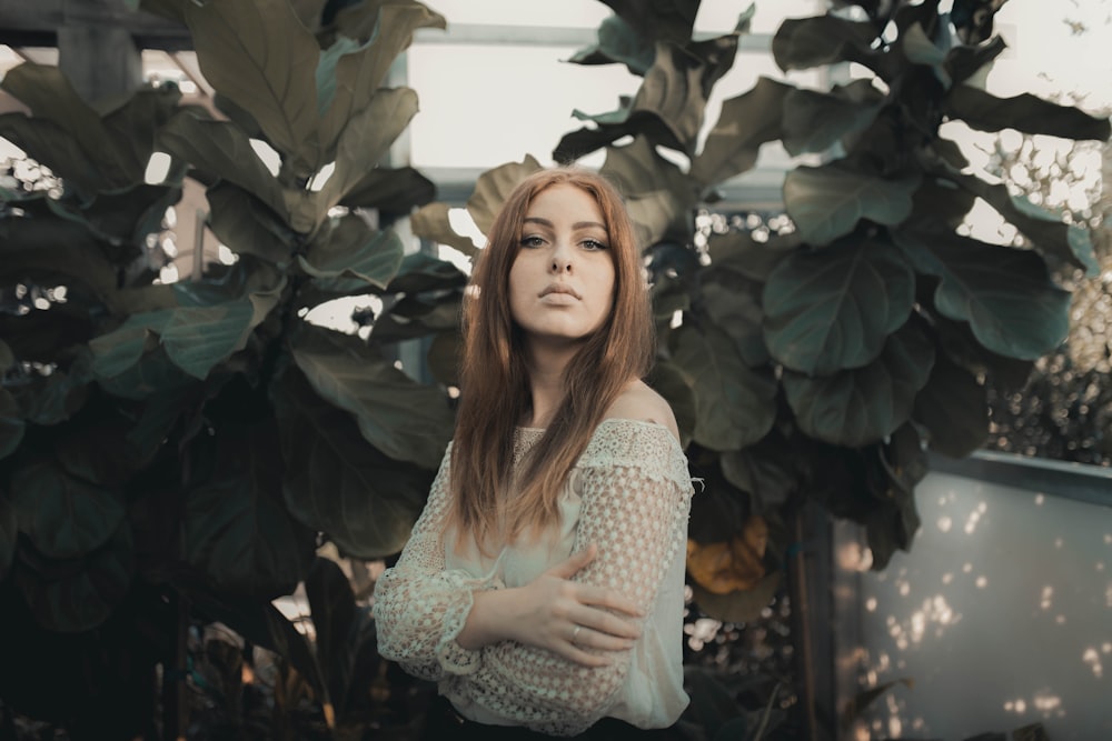 woman in white and black polka dot dress standing beside green leaves