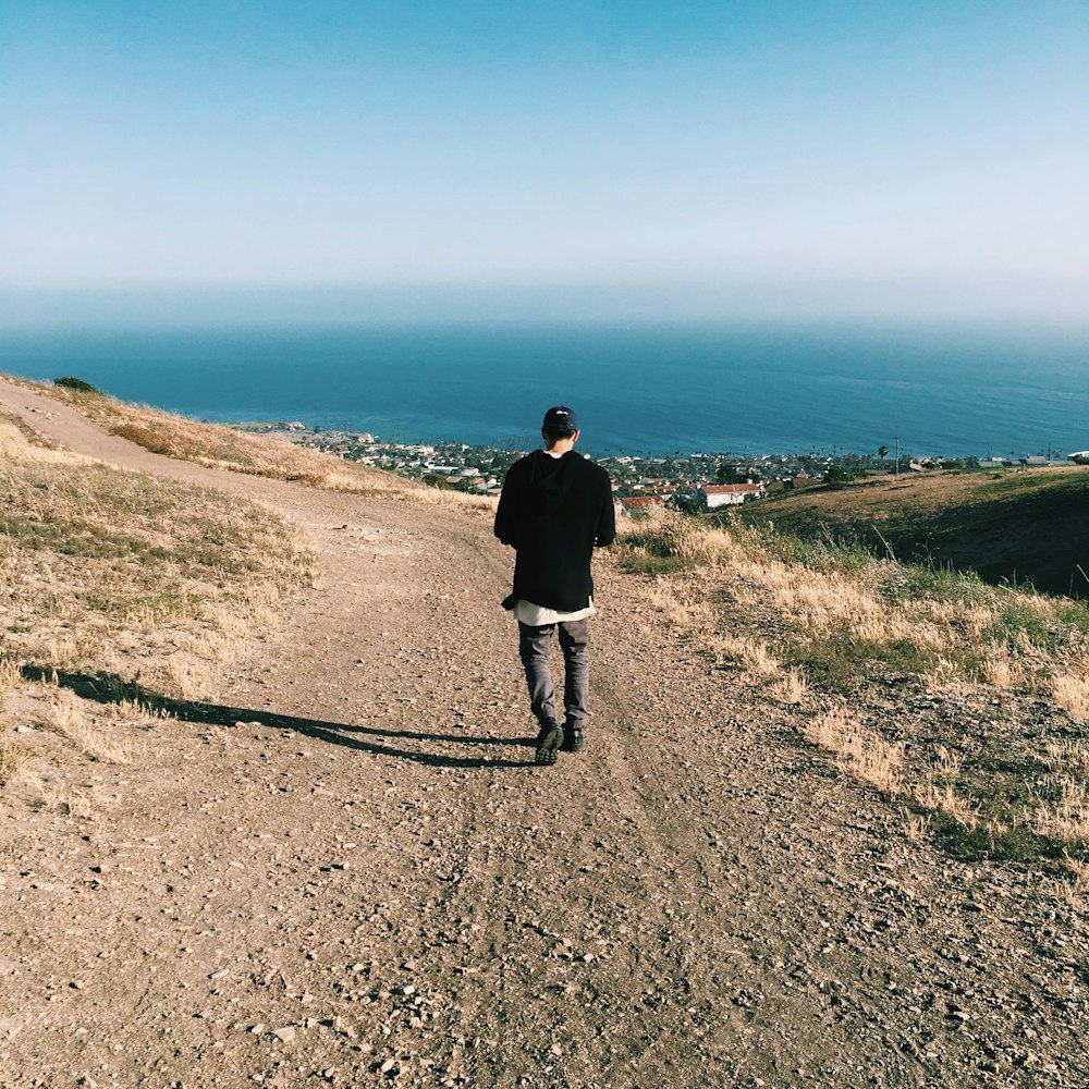 man in black jacket walking on pathway during daytime