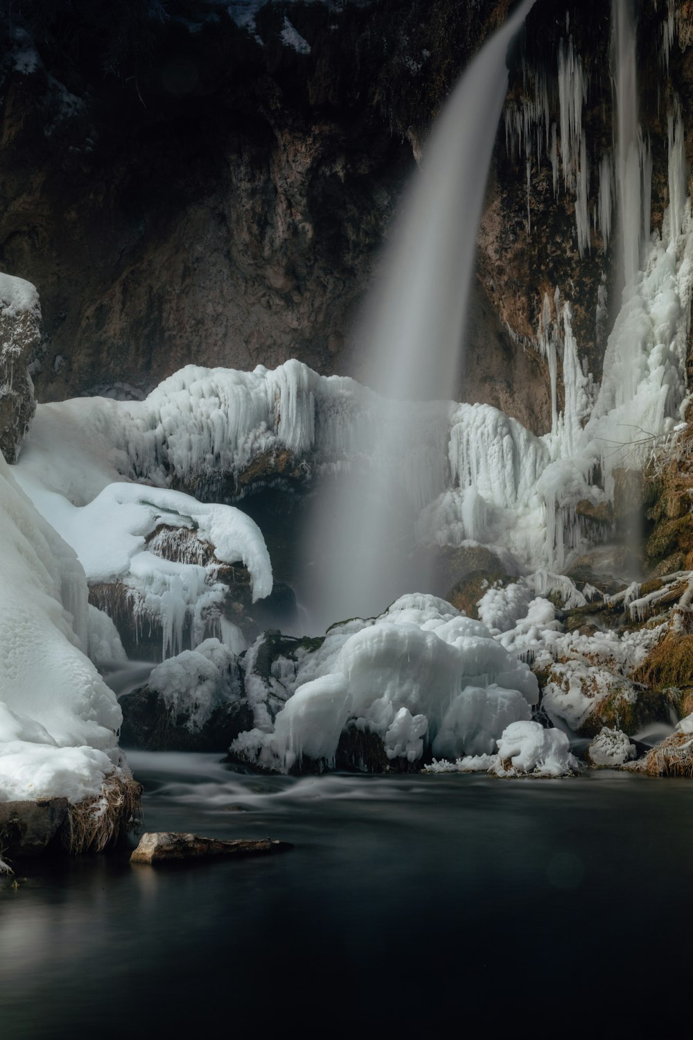 water falls in the middle of brown rocky mountain